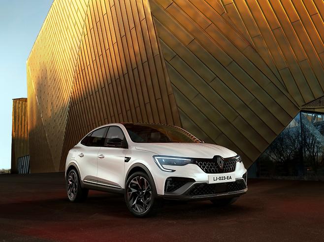 모던한 건축물 앞에 주차된 흰색 르노 SUV.